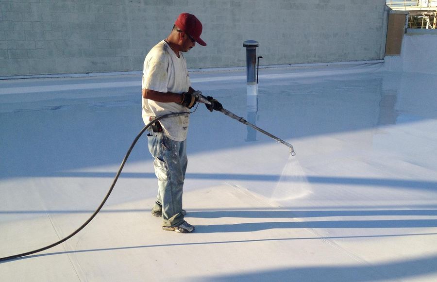 Crew spray-applying a silicone roof coating